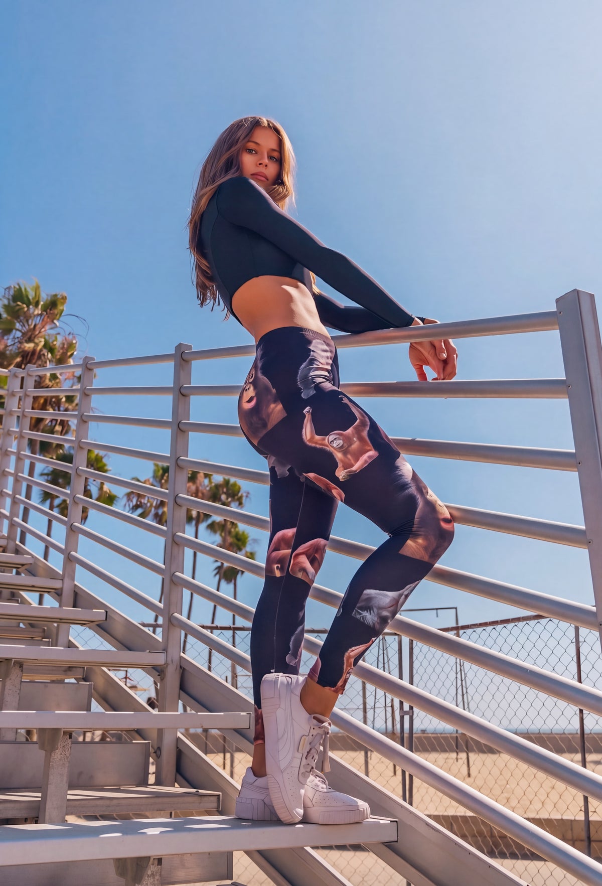 Woman leaning on a stair railing wearing the Gorilla Monkey Print Yoga Leggings, side view