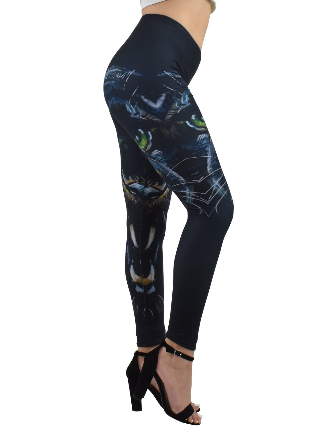 Side view of Denimaxx Enraged Black Puma leggings showing the black puma face with green eyes, styled with black block heels on a white studio background.