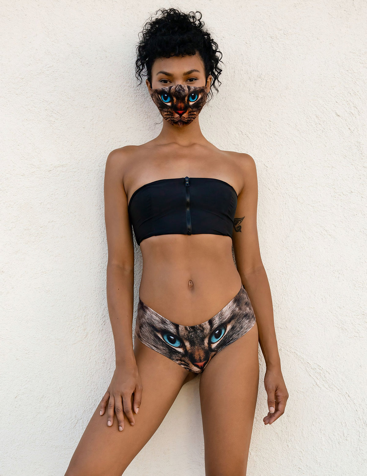 Front view of woman wearing Green-Eyed Cat print panties with a black strapless top and matching cat face mask.