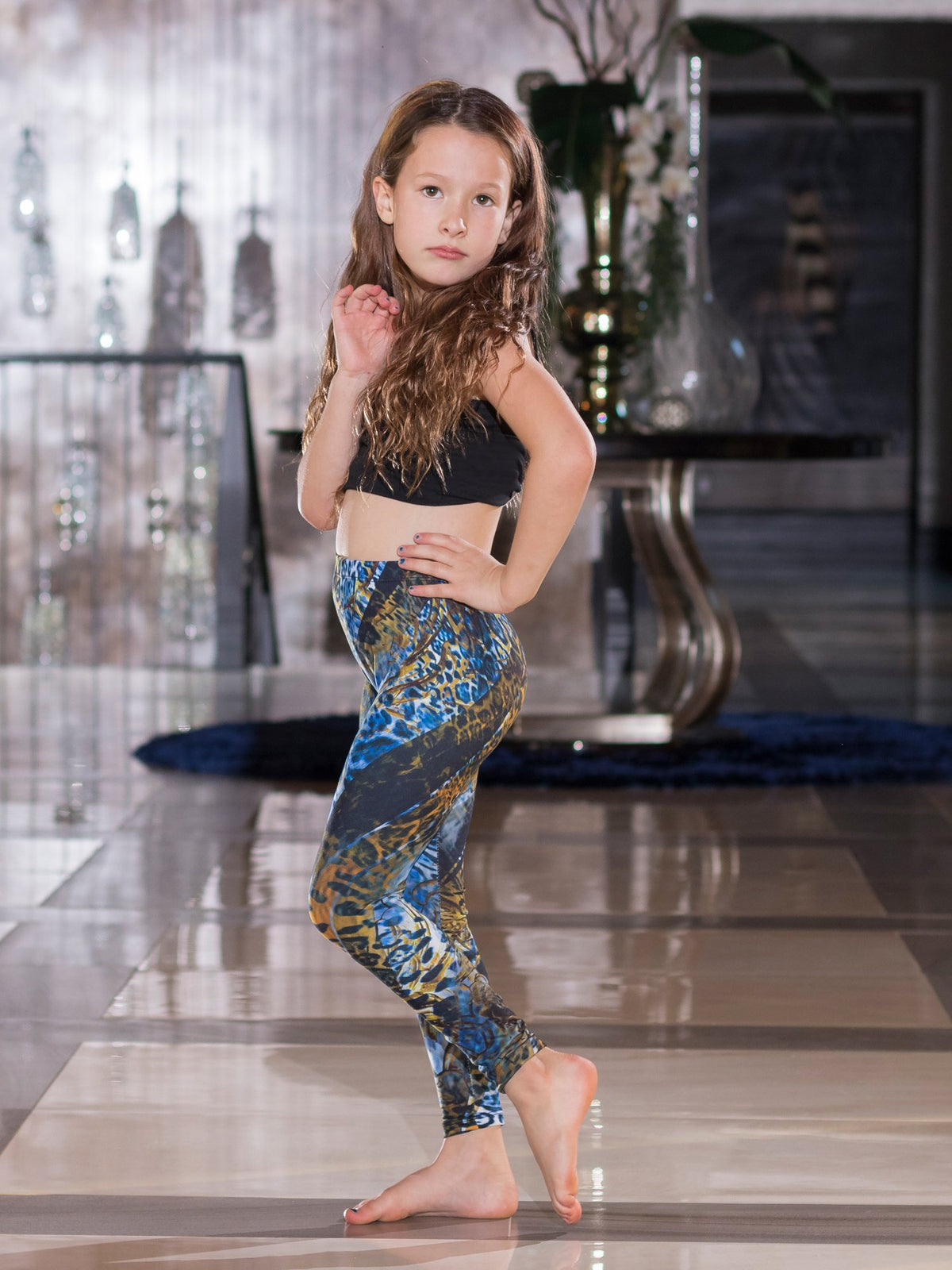 Young girl posing with hand on hip wearing kids Blue Snake print leggings with blue and gold snake scale print.